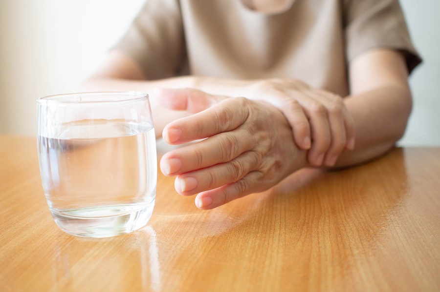 ruke starije osobe koja poseze za casom a boluje od parkinsonove bolesti